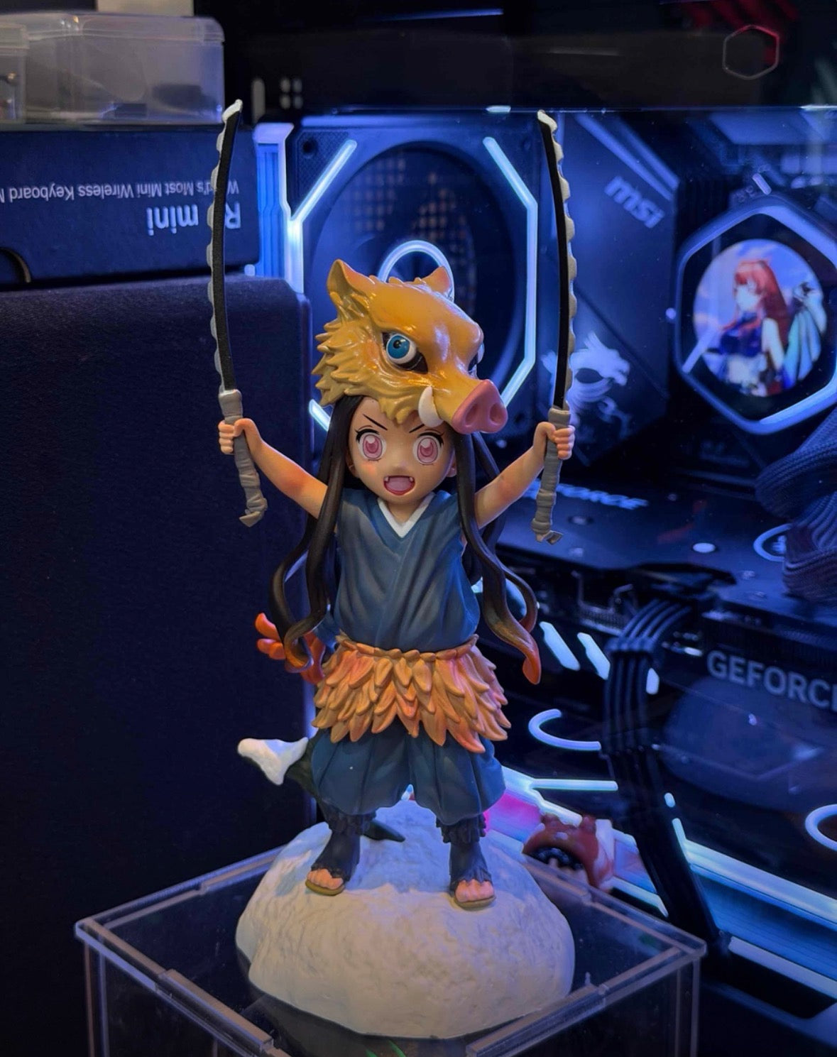 Animated character figurine with a fox on a stand in front of a computer setup.