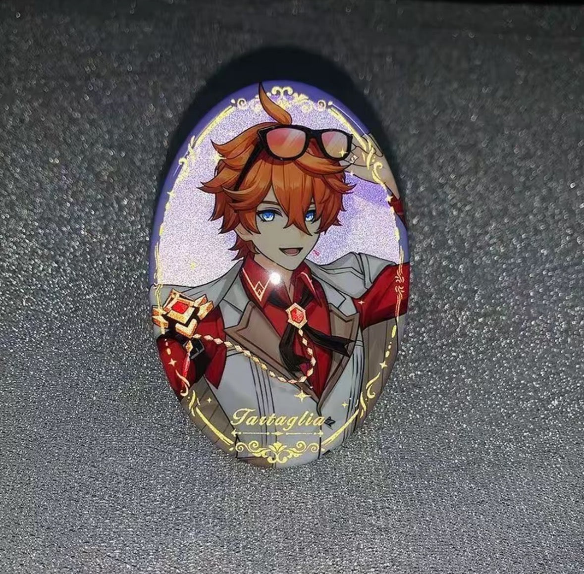 Oval-shaped brooch with anime-style character design on a dark background